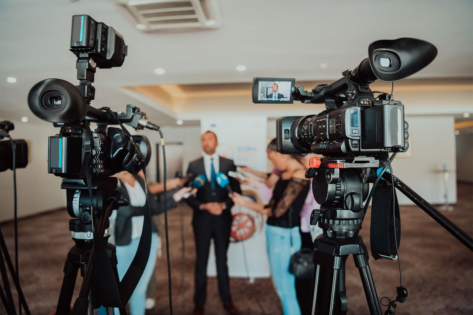 Press conference — cameras, journalists, spokesperson under scrutiny